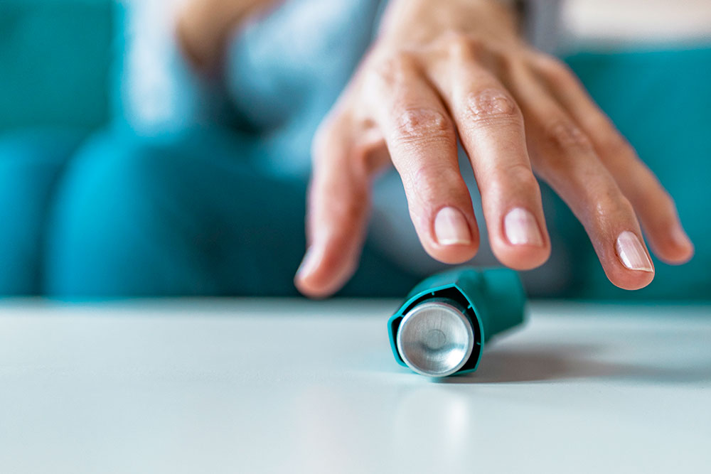 Hand som sträcker sig efter en astmainhalator